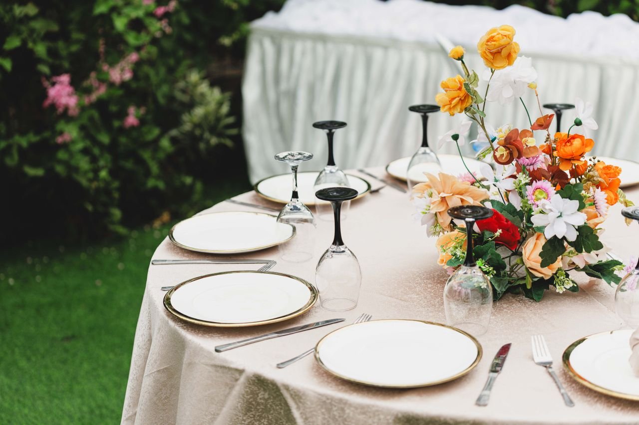 Beautiful outdoor dining setup with floral centerpiece and fine tableware, perfect for elegant occasions.